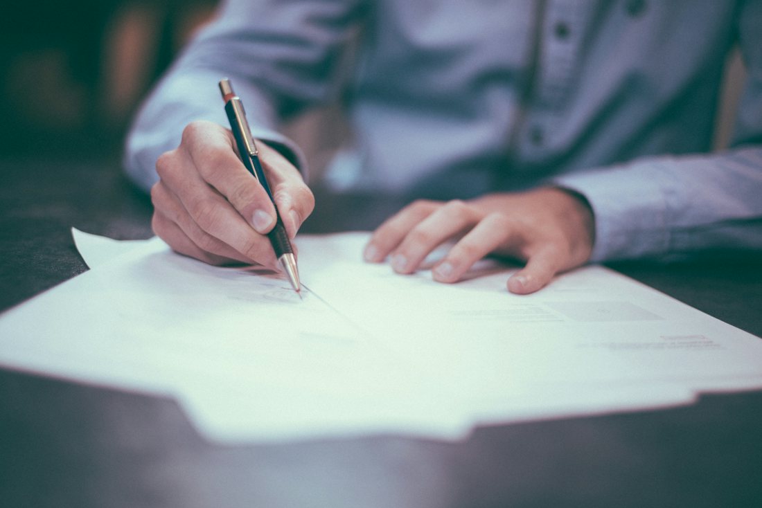 Printed financial plan documents on a desk with a pen